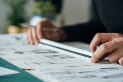Close Up Photo of Architect Hands Drawing Blueprint Design. 
Unrecognizable furniture designer sketching drawing design of plant stand using a paper, pen and ruler while sitting at his desk.
