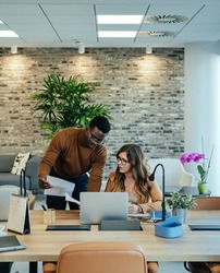 Corporate Business: Two Business Persons Analyzing Documents Together at Work. 

Businessman showing papers to businesswoman and talking about new project in modern office.
