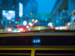 Digital clock inside sedan car in evening twilight time in Bangkok road, Thailand