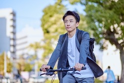 Young Japanese man in a jacket riding a bicycle