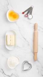 Ingredients and shapes for baking cookies on marble table. Concept cooking with love, cooking for your loved ones, baking for valentines day. Top view. Copy space