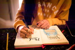 Closeup of young teen girl writing in bullet journal on mood tracker page