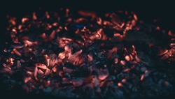Little pieces of burning ember after the fire. Glowing incandescent embers texture. close up.