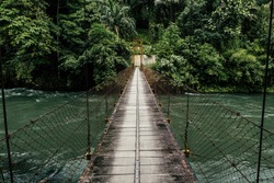 Suspension Bridge crossing the world famous clear water rapid of Asahan River surrounded by dense rainforest is perfect for kayak and white water rafting, North Sumatra, Indonesia.