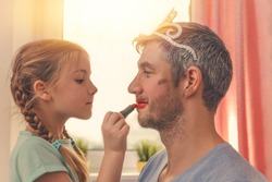 dad with cute daughter beeing treated with lipstick for carnival