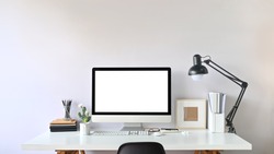 Photo of Contemporary Workspace.
White blank screen monitor on modern working desk. Equipment on table. Modern office concept. 