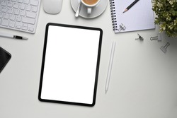 Mock up digital tablet with blank screen, plant and office supplies on white office desk.