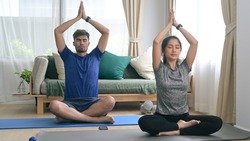 Peaceful young couple meditating, sitting in lotus position on mats. Healthy lifestyle, yoga, pilates, exercising concept