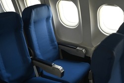 Airplane cabin interior, empty comfortable seats in economy class with portholes