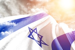 Israel national flag cloth fabric waving on beautiful grey sky.