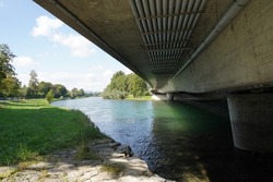 Beam bridge over river Limmat in canton Zurich, Switzerland. Low angle view showing cement pillars planted in the water. There are pipes attached to the bridge and crossing the river as well. 