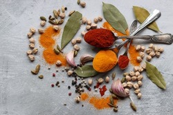Vibrant colors of aromatic spices. Colorful still life with turmeric, paprika, peppercorns, chili, garlic, bay leaf, sea salt. Food flavoring. 