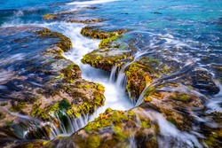 Long exposure view of wave and waterfall on sea rock with green laver at Mopo-ri near Pohang-si, South Korea  
