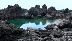 High angle view of Socheonji Pond at the center of volcanic rocks on the sea near Seogwipo-si, Jeju-do, South Korea 
