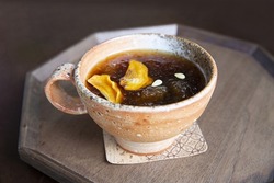 Close-up of Sujeonggwa(persimmon punch) with ice and dried persimmons in a ceramic cup, South Korea
