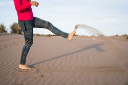 Woman's feet kicking sand in coastal dunes in south america