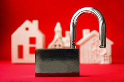 Open metal padlock on red background with white houses, insecurity and invasion concept