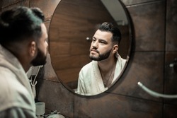 Bearded man in a bathrobe in the bathroom. Groom morning prepare for wedding at the hotel. Fashion photo of a man.