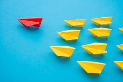 Leadership concept. Red paper plane origami leading among small yellow planes on blue background. Leadership skills need for top management in organization, company ex: supervisor, manager, CEO, CFO.
