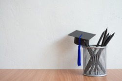 Graducate cap and black pencils on table with white wall background copy space - Back to school, education and scholarship abroad concept. Education is future planning.