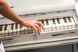 fingers of a young student's hands play excellent music from the keys of the old piano