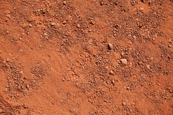 Texture of dry red clay with stones close-up