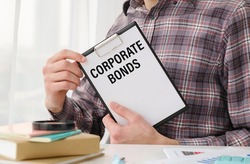 businessman writes in Clipboard text: corporate bonds. Business and education concept.
