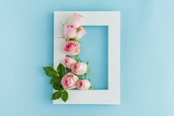 Flowers composition. Photo frame, rose flowers on pastel blue background. Valentines day, mothers day, womens day, spring concept. Flat lay, top view, copy space