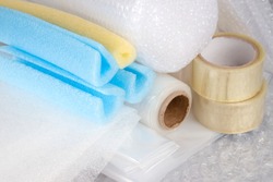 Set of plastic packaging materials - plastic stretch film rolls, foamed polyethylen sheets and rolls, transparent scotch tape, foam edge protectors, small and large bubblewrap rolls. Selective focus