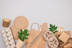 Eco-friendly sustainable packaging and tableware set - kraft paper food packaging on gray background with copy space. Street food paper packaging - cups, plates, straws, containers, paper bags