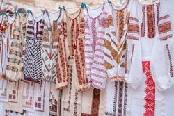 Different Ukrainian vintage clothes - traditional embroidered shirts, vyshyvanka. Traditional ukrainian dresses on flea market Vernissage in Lviv, thrift shopping concept. Selective focus