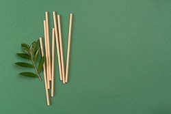 Banner with mockup image of kraft paper drinking straws on green background with copy space and green fresh leaves around. Sustainable lifestyle and zero waste concept. Ethical consumerism. Flat lay