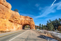 View of Red Rock Arch Tunnels in Red Canyon or Iconic Bryce Canyon gateway tunnels with blue sky background.
