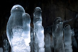group of transparent ice stalagmites in a cave closeup on a dark background