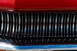 background - fragment of the front of used vintage car: grille, bumper and a fragment of the red hood