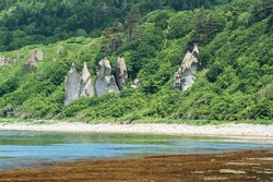 coastal landscape, beautiful lava rocks on the green coast of Kunashir island, algae on the littoral at low tide
