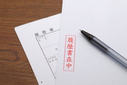 Red Japanese characters on a white envelope. Translation: with resume, resume, furigana, name, year, furigana, address.