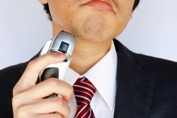Asian businessman with beard. He's holding an electric shaver.
