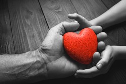 red heart in hands on a dark background, the concept of love and care for loved ones and needy.black and white.