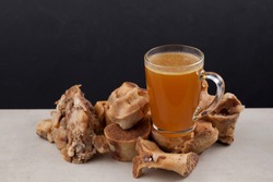 Transparent Cup of bone broth is placed on boiled beef bones, which contain the necessary amino acids for the body. Selective focus