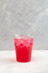 Red refreshing iced cocktail in disposable plastic cup. Summer fruit and berry drink. Take away, street food. Boba drink or bubble tea.
