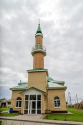 a mosque against the sky. a yellow Muslim mosque against a gray cloudy sky, surrounded by green spaces. High quality photo