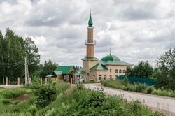 a mosque against the sky. a yellow Muslim mosque against a gray cloudy sky, surrounded by green spaces. High quality photo