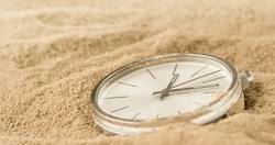 Pocket watch on a sand lost in time, closeup antique watch and a thin line of focus