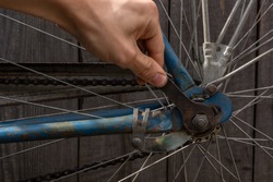 fixing an old rusty bike with a wrench; turns the nuts with a wrench on the wheel of an old bike