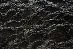 abstract grey black texture of the mountain cascades is like being on another planet. Black texture of geothermal springs, geysers. Gray stone background with craters. Top view. Dark Meteor texture