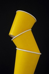 Stack of yellow coffee cups on black background