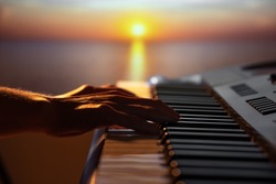 Girl playing a synthesizer at sunset