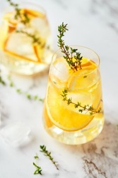 Refreshing cocktail with ice, orange and thyme. Refreshing summer homemade alcoholic or non-alcoholic cocktail or mocktail, or Detox infused flavored water.