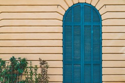 Arched door in blue on a yellow wall